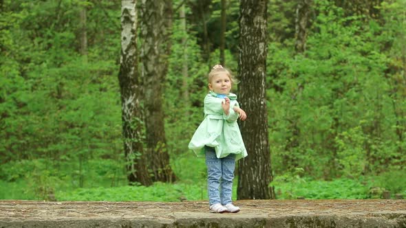 A little beautiful girl dancing in a green forest.  It's spring.
