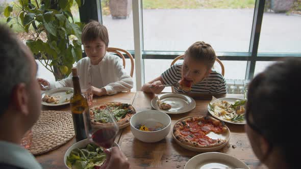 Top View, Boy Takes a Food From a Plate, Girl Eats Pizza alt