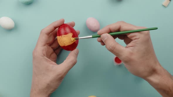 Hand of a Man is Painting Colored Easter Eggs alt