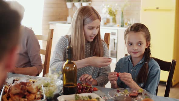Two Little Sisters Eating Grape at Family Dinner alt