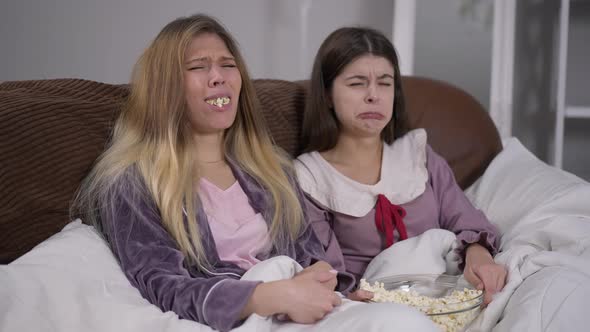 Two Young Absorbed Women Watching Movie on TV Start Crying Sympathizing Actors alt