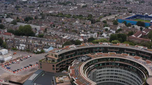 Backwards Reveal of Round Ring Television Centre Building and Rows on Family Houses in Urban alt