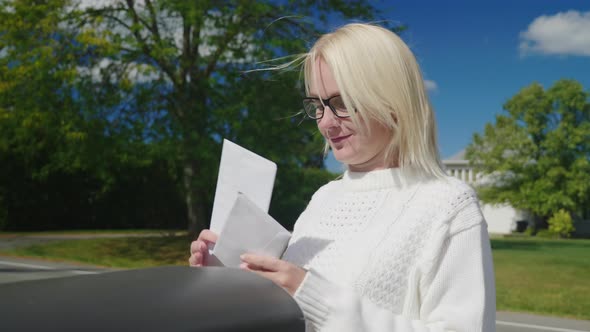 A Woman Puts the Letters in the Mailbox and Picks Up a Red Flag for the Postman alt