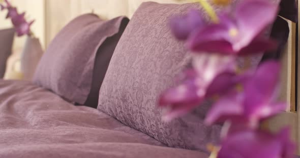 Closeup of Purple Pillows with Floral Patterns and Purple Cover on the Bed alt