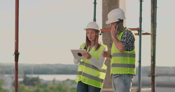 Building in Construction with a Female and a Male Engineers Using a Tablet and Mobile Phone to alt