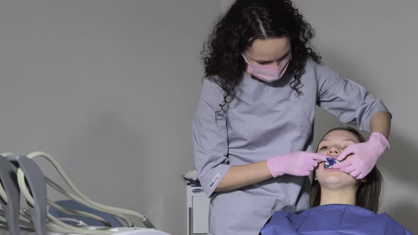 The orthodontist using dental impression tray on woman teeth alt