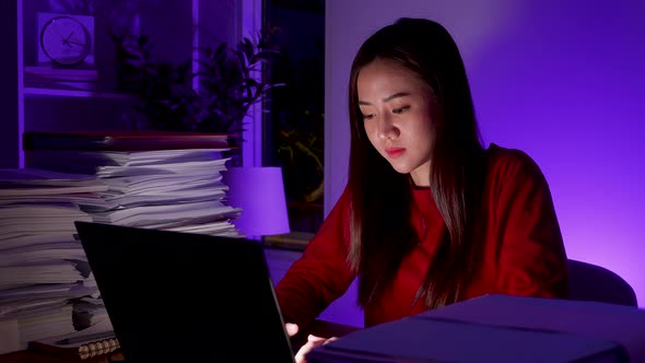 Asian businesswoman on desk work overtime doing deadline project, late time business.