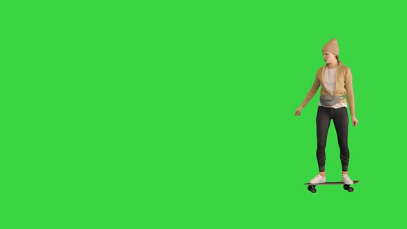 Young Stylish Woman in a Hat Skateboarding on a Green Screen Chroma Key