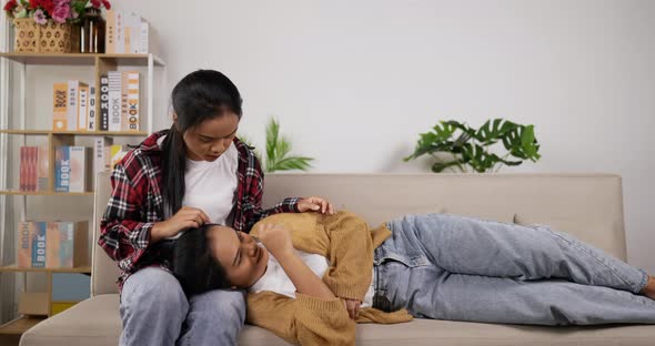 Asain twin girls, Younger sister lying on older sister leg while fever alt