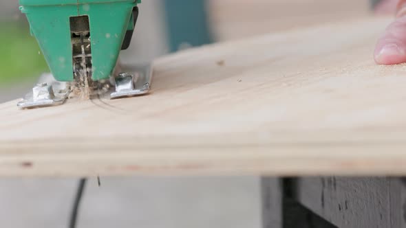 Sawdust Flies Off a Metal Blade As the Jigsaw Cuts Into a Sheet Plywood Workpiece alt