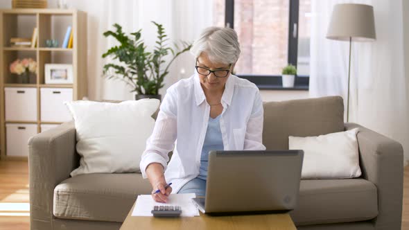 Senior Woman with Laptop and Calculator at Home  alt