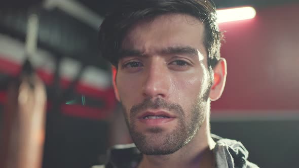 Close-up shot of Caucasian young male athlete or sportsman standing in the dark of gym stadium. alt