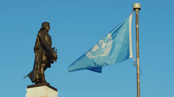 United Nations flag near a statue alt
