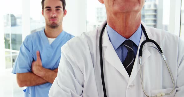 Portrait of male doctors and coworker standing with arms crossed alt
