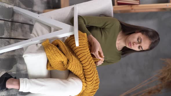 Young Woman Knitting a Woolen Sweater with Thick Yarn Knit on Needles Sitting at Home in a Cozy alt