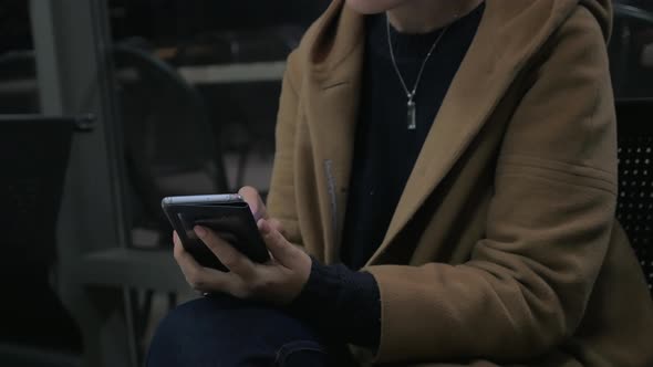 Young girl sits on a chair, holding a mobile phone alt