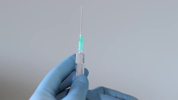 Extreme close up shot of doctor's hands wearing surgical gloves and squirting air from syringe throu alt