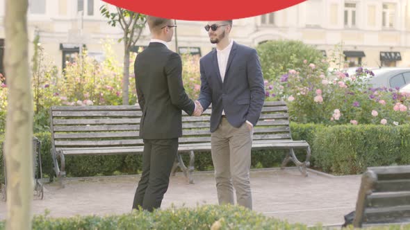 Two Young Caucasian Men in Suits Meeting Outdoors and Shaking Hands As Prohibition Sign Appearing alt