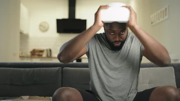 Young Black Man Putting on Video Glasses at Kitchen. Upset Guy Taking Off Vr alt