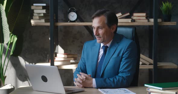 Happy Mature Male Businessman CEO Having Video Call Using Laptop Computer While Sitting at Office alt