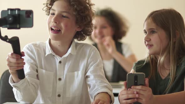Portrait of Funny Schoolboy Blogger Curlyhaired Teenage Boy with a Steadicam in His Hands alt