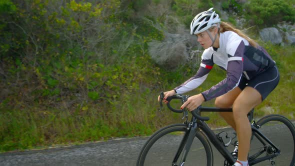 Female cyclist cycling on a countryside road 4k alt