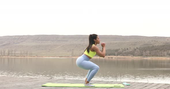 Young beautiful black woman in sportswear doing squat. Outdoor fitness.