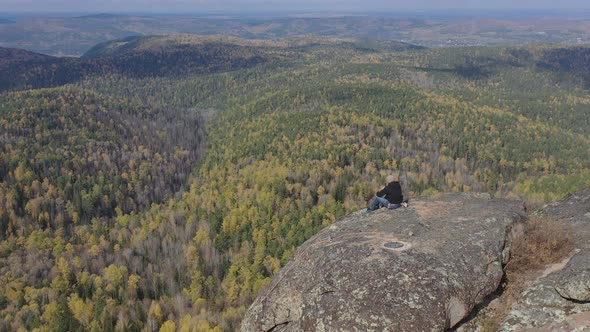 A Lone Male Climber Sits on Top of a Mountain and Enjoys a Beautiful View of the Gorge