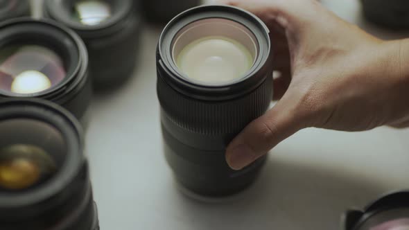 A hand putting down the lens of the camera between another lens. alt