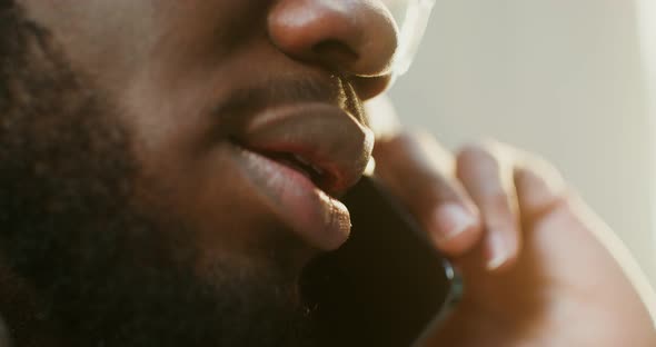 AfricanAmerican Man is Using a Mobile Phone While Walking in the City alt
