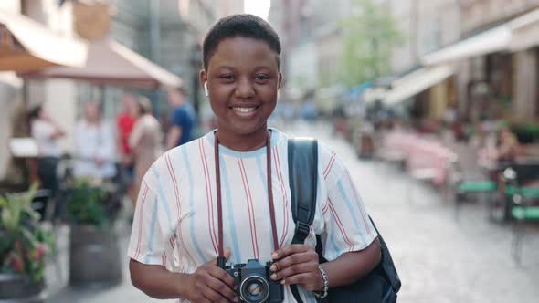 Pretty African Woman with Backpack Standing on City Street alt