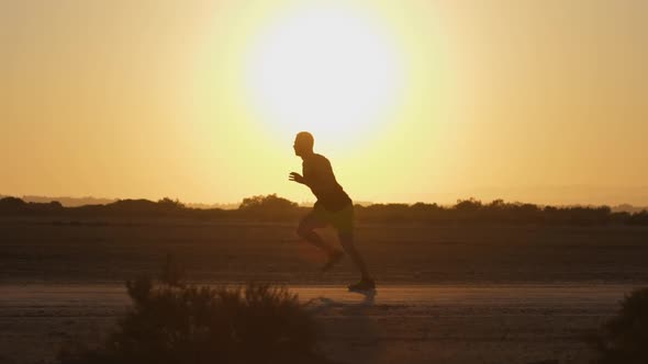 Sporty Man Running in Desert at Sunset Side Shot