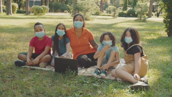 Schoolchildren and Teacher in Medical Protective Face Masks Outdoors alt