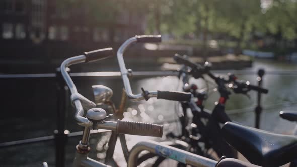 Bicycles are Parked By the Amsterdam Canal on a Sunny Day