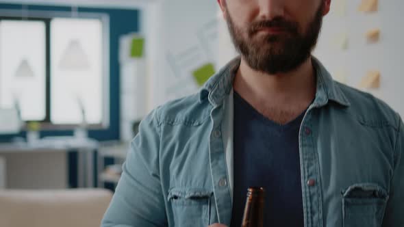 Portrait of Businessman Holding Bottle of Beer After Work in Office alt