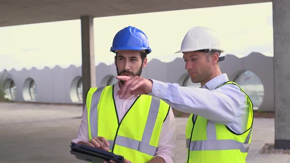 Male architect discussing with digital tablet at construction site