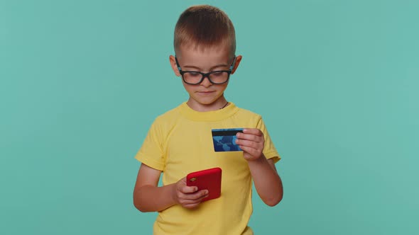 Children Boy Using Credit Bank Card Smartphone While Transferring Money Purchases Online Shopping alt