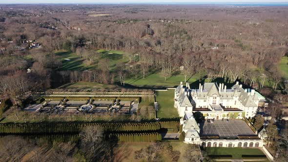 An aerial view over an upscale, luxury mansion with an eight reflection pool fountain, on Long Islan alt