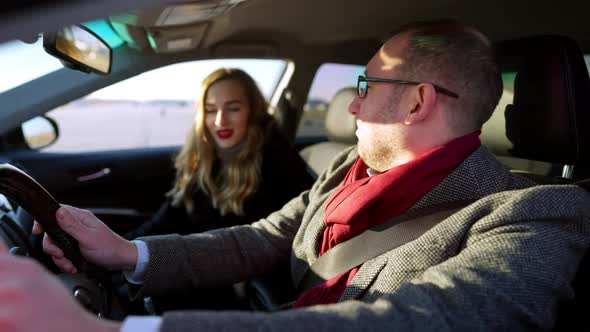 Stylish Happy Rich Man Giving Highfive in Slow Motion To Smiling Young Woman Sitting on Passenger alt
