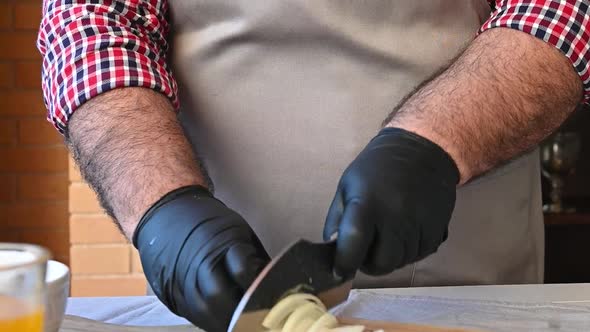 Man in Gloves Cuts Onions on a Cutting Board