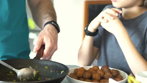 Boy talking to his father while dinner is prepared