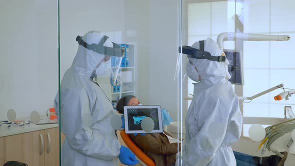 Dentist Doctors in Overall Using Tablet Explaining Dental x Ray alt