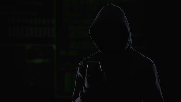 Male Hacker Activating Spyware on Smartphone, Collecting Private Information alt