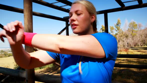 Determined woman performing stretching exercise during obstacle course alt