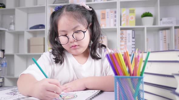 Asian girl wearing glasses is doing homework for school at the white deck alt