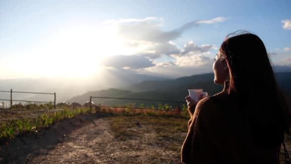 Slow motion of a female traveler drinking coffee while watching sunrise in the morning