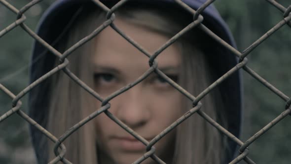 Portrait of Moody and Sad Blonde Caucasian Girl Behind the Iron Fence. Young Woman Behind Metal alt