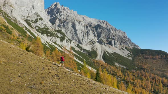 4K Aerial View Woman Hiking High up in Mountains on Sunny Autumn Day alt