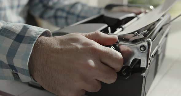 Man sitting at desk and typing on a typewriter