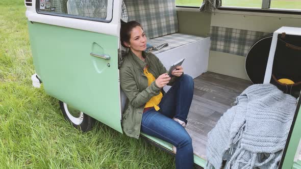 Woman sitting in camper and using tablet